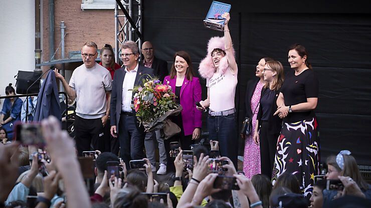 Nemo, der Bieler Gemeinderat und Grossratspräsidentin Dominique Bühler auf der Bühne bei der Geschenkübergabe - ein Pokal und ein Blumenstrauss